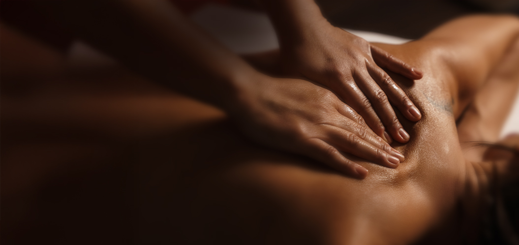 Eine Person erhält mit entspanntem Gesichtsausdruck eine Rückenmassage bei sanftem Licht